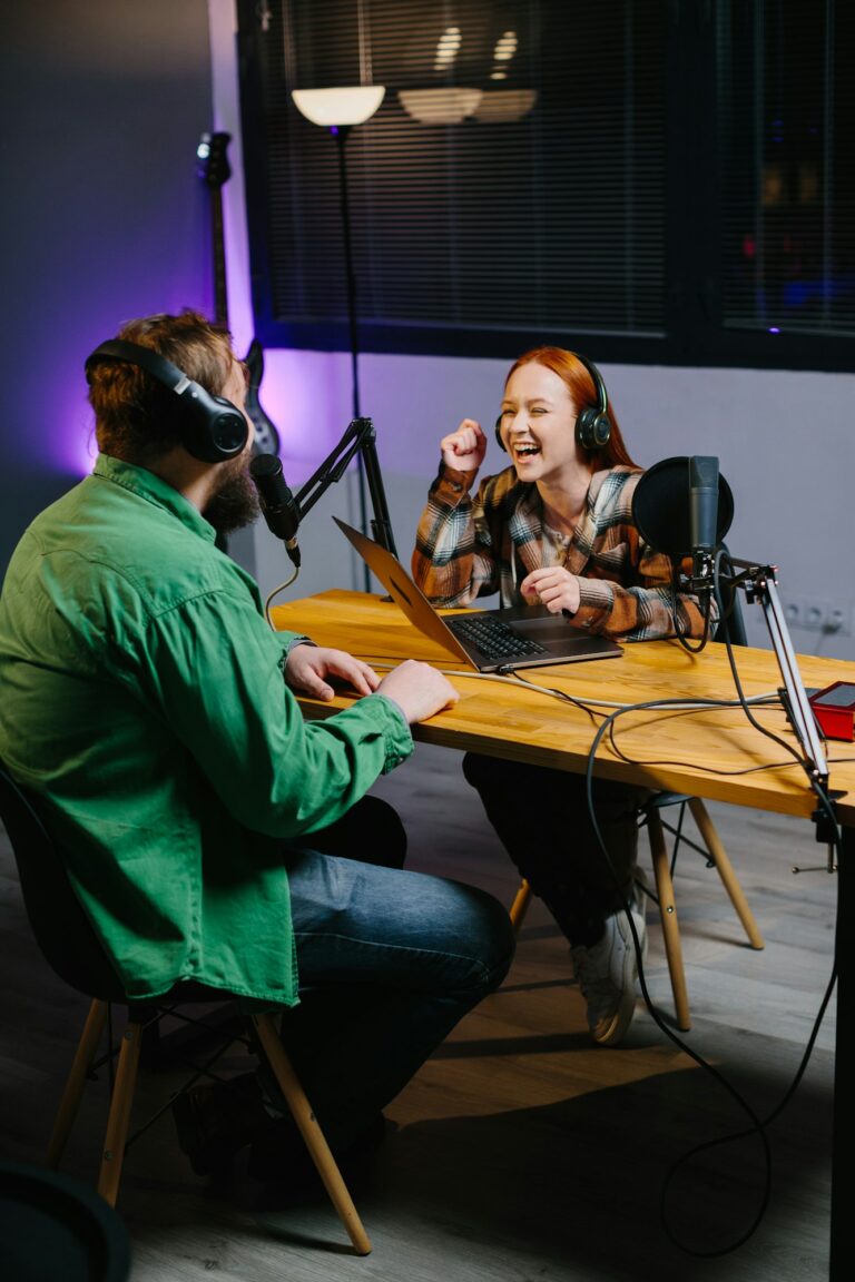 A podcast host and a guest have fun chatting during a live online broadcast in a home studio.