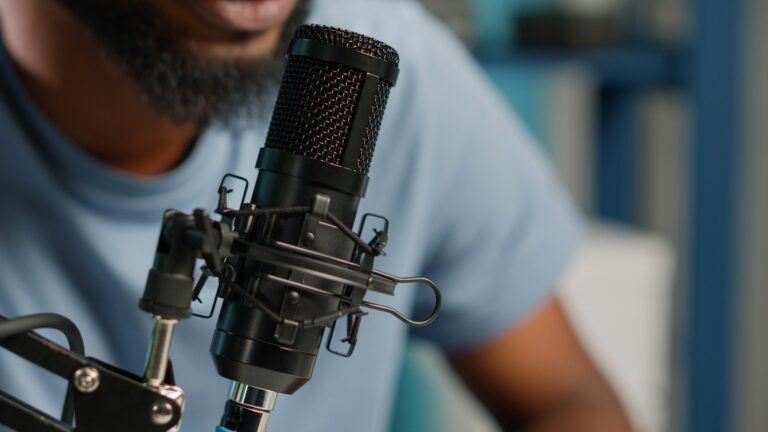 Close up of black vlogger using microphone on podcast