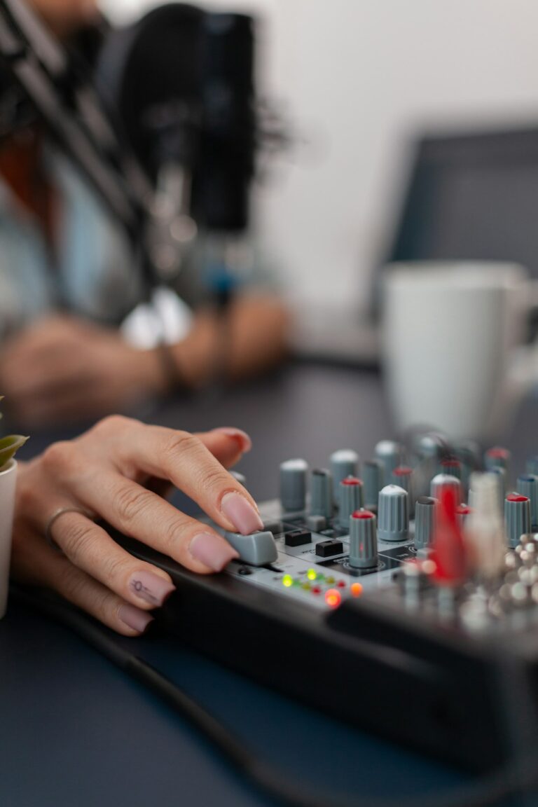 Closeup of hand pushing controls on sound mixing console