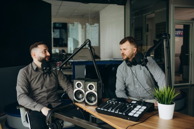 two smiling radio hosts talking while recording podcast in broadcasting studio