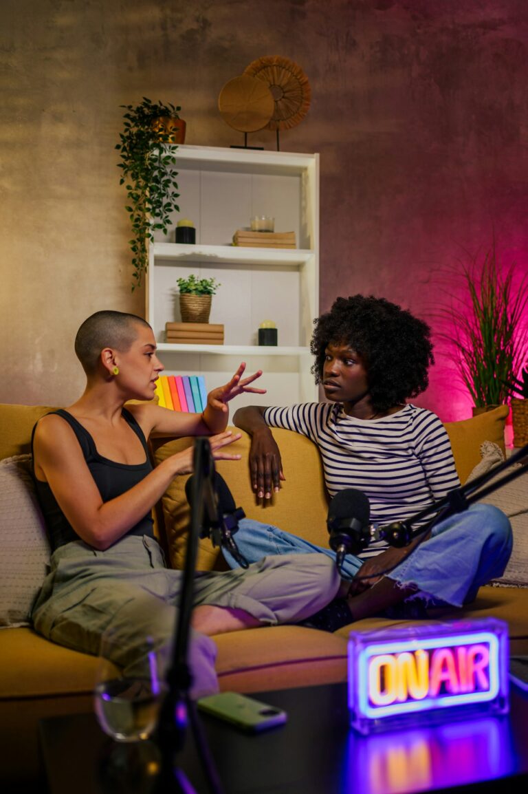 Vertical photo of two diverse women recording internet podcast in a studio